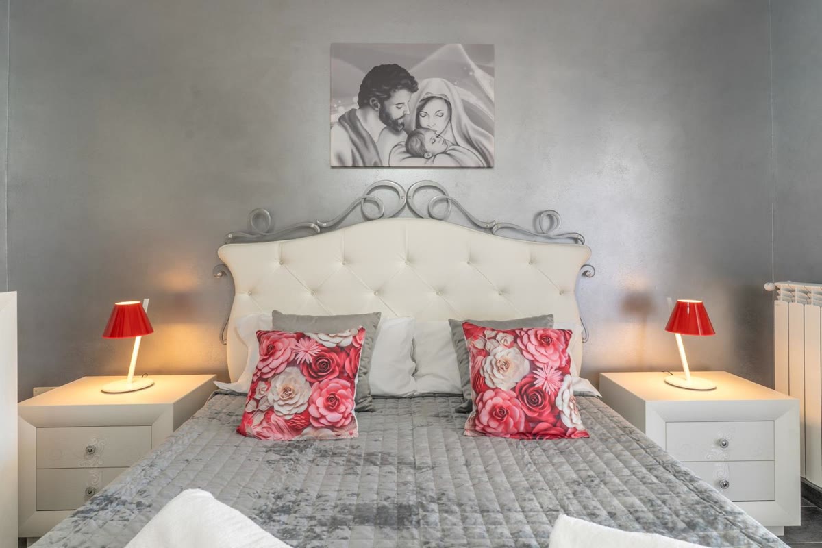 Camera Sole: letto matrimoniale con la testata capitonnè e le lampade rosse
